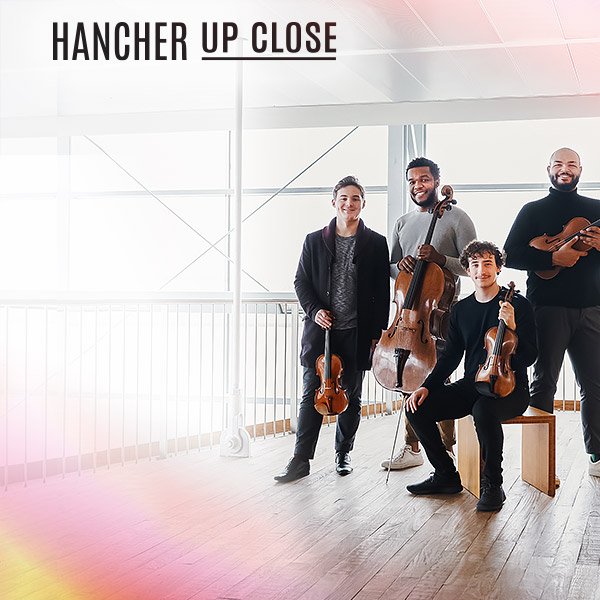Isidore String Quartet smiling at the camera holding their instruments