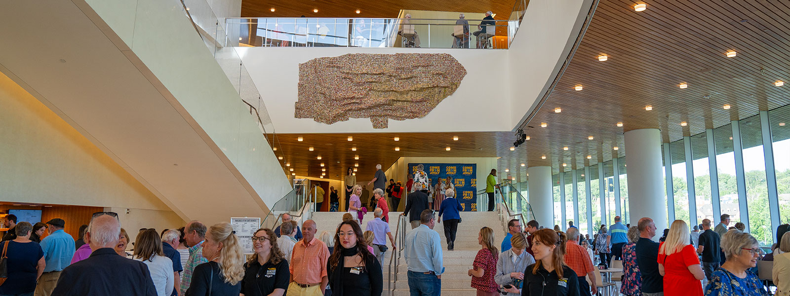 image of the artwork hanging in the entrance of Hancher's lobby with people
