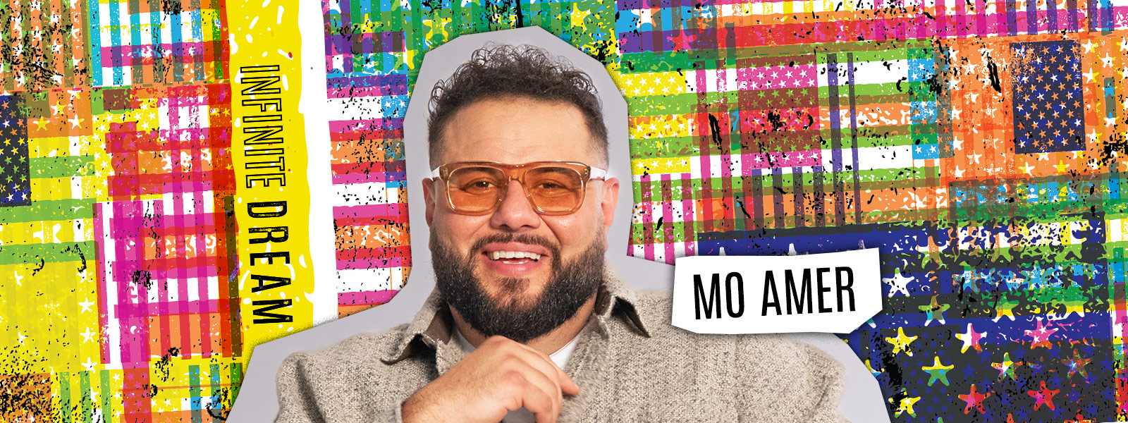 Mo Amer smiling while wearing orange sunglasses
