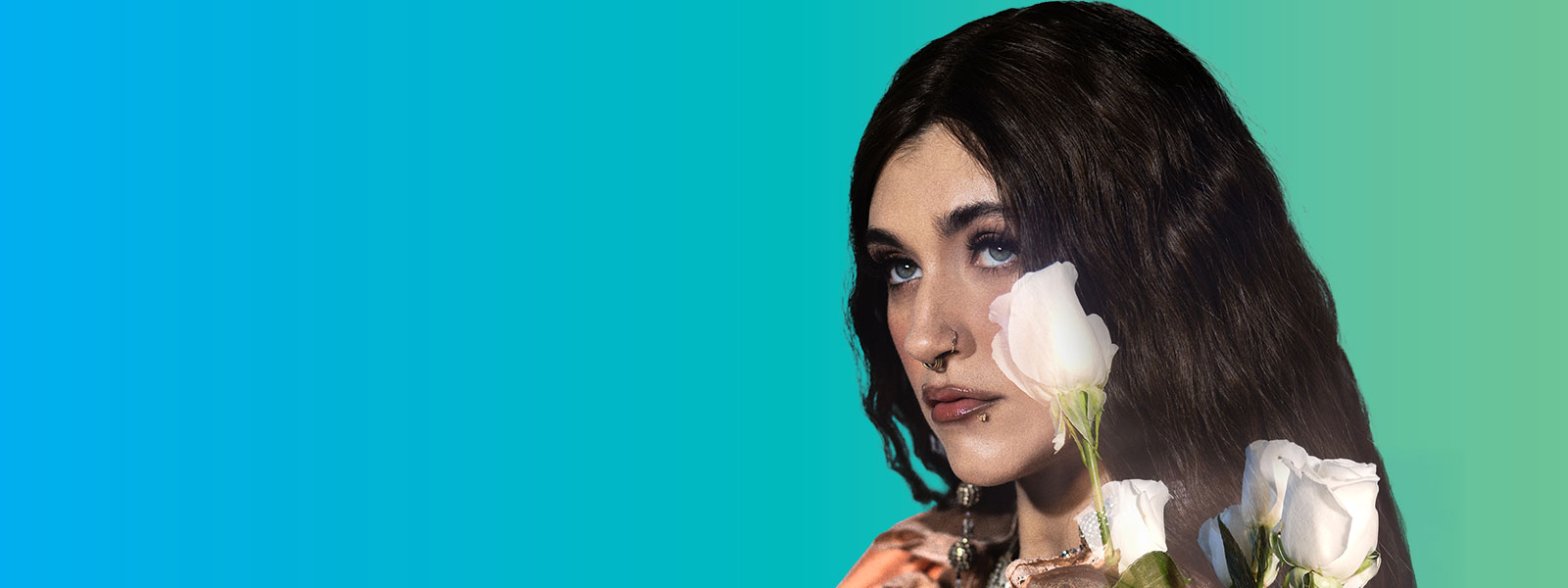 Sierra Ferrell looking up into the distance with white roses covering part of her face and hair