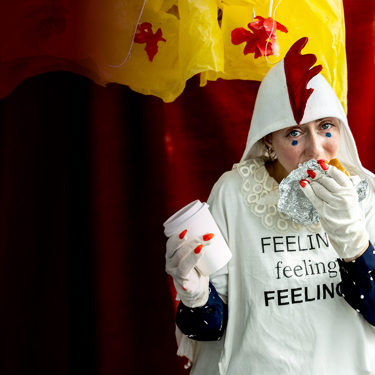Alex Tatarsky wearing a chicken costume while eating a chicken sandwich