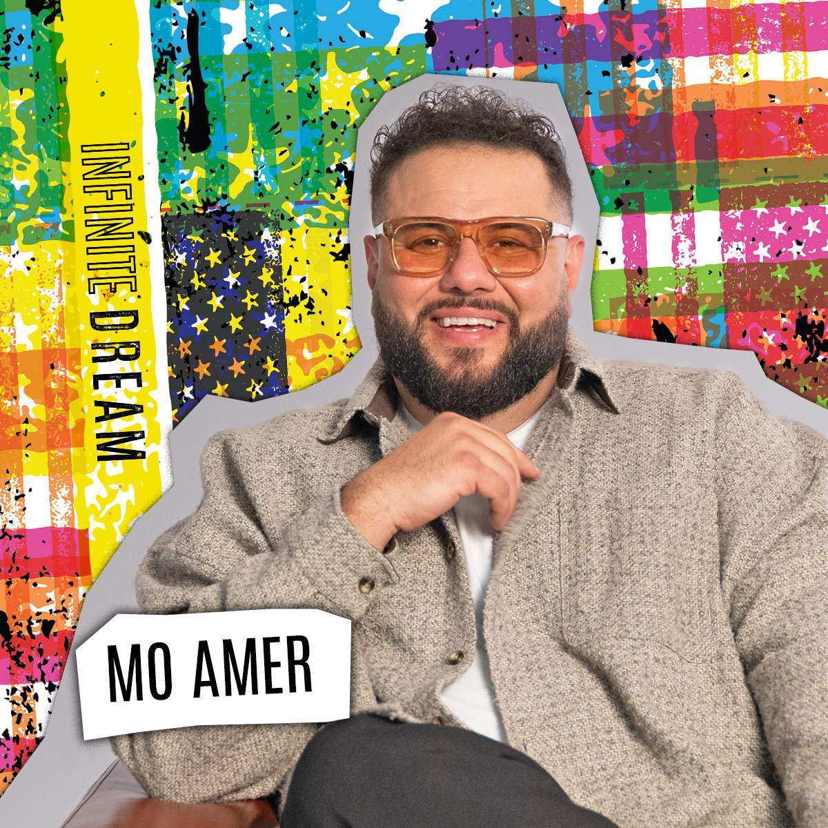 Mo Amer smiling while wearing orange sunglasses