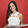Smiling Alexa Tarantino in white shirt holding a saxophone against a red background