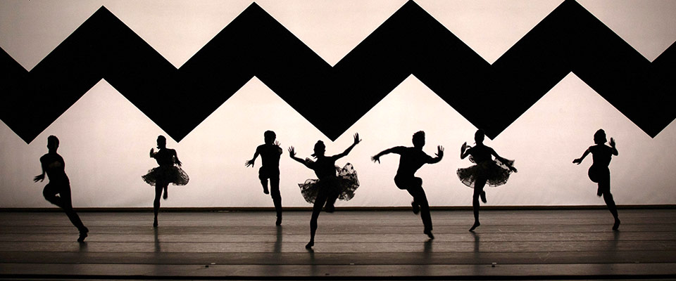 Dancers from American Ballet Theatre dance in silhouette against a background with a giant zig-zag pattern