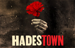 Hadestown card image: a hand coming out of the shadows holding a red flower 