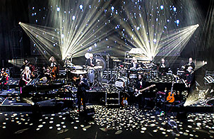 Mannheim Steamroller performing on stage while white strobe lights surround them