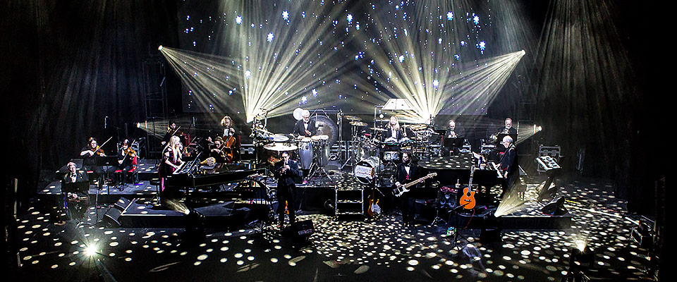 Mannheim Steamroller performing on stage while white strobe lights surround them