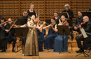 Midori playing standing center stage playing violin with Festival Strings Lucerne 