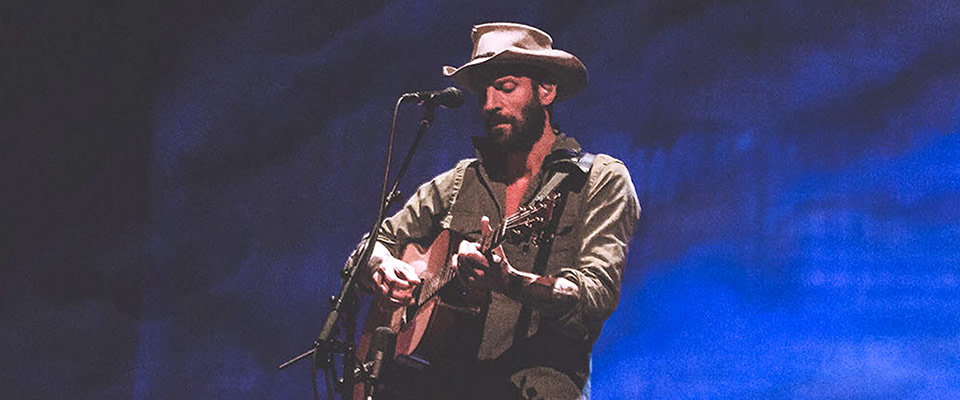 Ray LaMontagne on stage playing a guitar