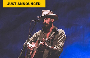 Ray LaMontagne on stage playing a guitar