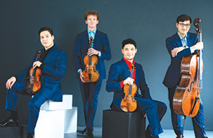 Schumann Quartet posed holding their instruments, all wearing a royal blue pant and jacket combo