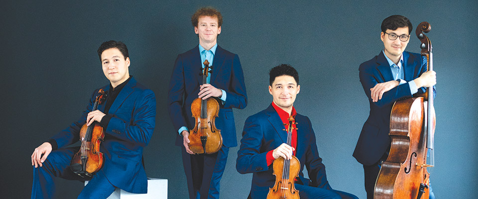Schumann Quartet posed holding their instruments, all wearing a royal blue pant and jacket combo