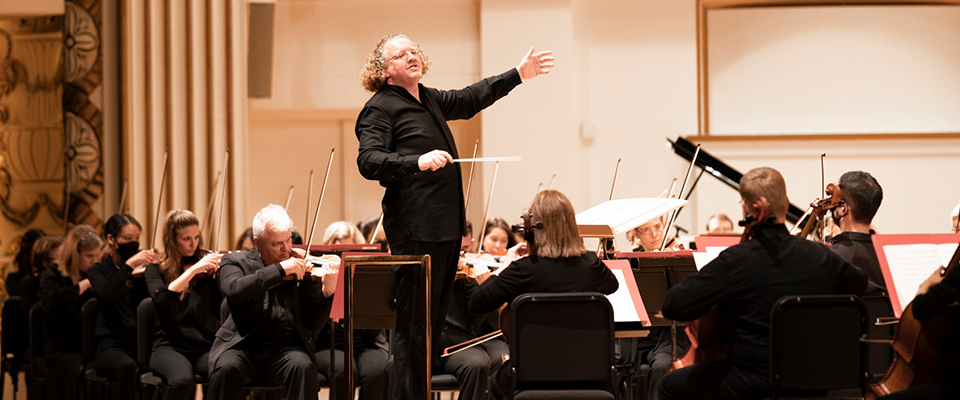 St. Louis Symphony Orchestra Music Director Stéphane Denéve standing in center of musicians with left arm out