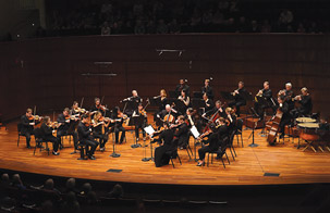Saint Paul Chamber Orchestra on stage during performance with image of Dmitry Sinkovsky playing violin in lower left of the banner