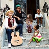 Dan + Claudia Zanes sit on the stoop of a brownstone home, sharing a laugh with three children