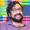 Hari Kondabolu headshot against Hancher's Infinite Dream colored flag treatment