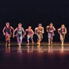 Twyla Tharp dancers in a line stepping forward in colorful costumes