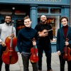 Isidore String Quartet standing looking at the camera while holding their insturments