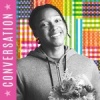 Josh Johnson standing against the Infinite Dream flag treatment. Johnson is holding a bouquet of flowers