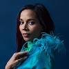 Side profile headshot of Rhiannon Giddens in blue outfit against a blue background