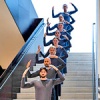 Trisha Brown dancers standing in a line up stairs with their hands raised above their head