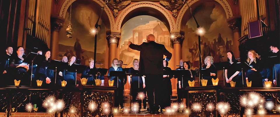 The Crossing Music Director Donald Nally with his back to the camera in motion conducting standing choir 