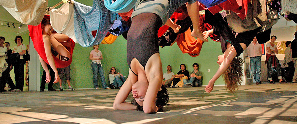 Trisha Brown Dance Company dancers hanging from fabric connected to the ceiling