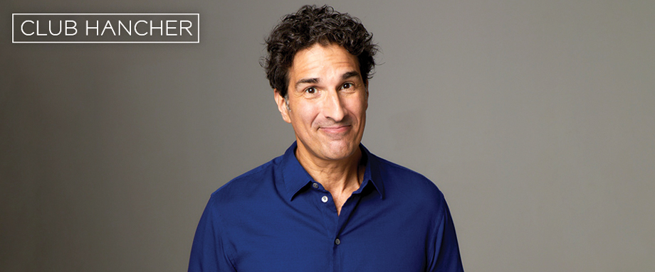 Gary Gulman wearing blue button down close-lipped smiling straight on at the camera. Club Hancher text treatment in upper left corner