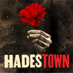 Hadestown card image: a hand coming out of the shadows holding a red flower 