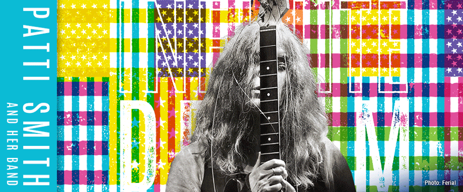 Patti Smith holding neck of her guitar in front of her face against Hancher's Infinite Dream colored flag background