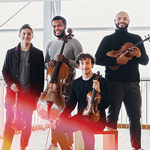 Isidore String Quartet Isidore String Quartet standing looking at the camera while holding their insturments