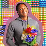 Josh Johnson standing against the Infinite Dream flag treatment. Johnson is holding a bouquet of flowers