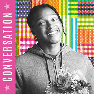 Josh Johnson standing against the Infinite Dream flag treatment. Johnson is holding a bouquet of flowers