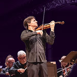 Joshua Bell and Academy of St. Martin in the Fields Joshua Bell playing while standing in the middle of an ensemble sitting down and playing string instruments