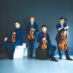 Schumann Quartet posed holding their instruments, all wearing a royal blue pant and jacket combo