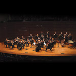 Saint Paul Chamber Orchestra on stage during performance with image of Dmitry Sinkovsky playing violin in lower left of the banner