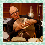 Steven Schick holding a cymbal while looking at the camera. 