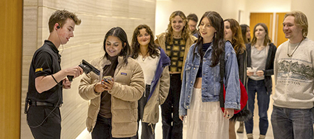 Student usher scanning tickets for a performance with a line of young UI students waiting for admission