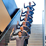 Trisha Brown dancers standing in a line up stairs with their hands raised above their head