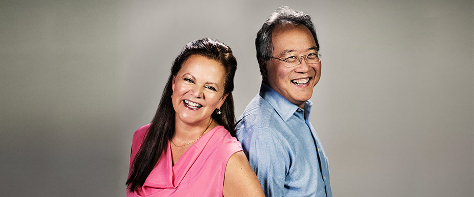 Yo-Yo Ma and Kathryn Stott stand back to back, laughing and smiling