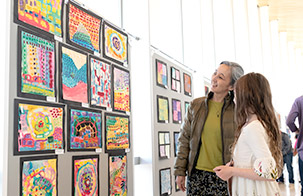 Two patrons looking at art on a wall to the left of them