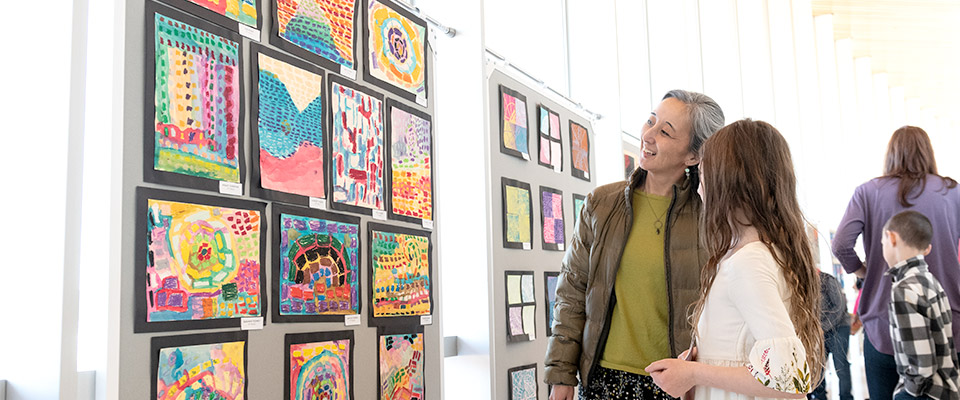 Two patrons looking at art on a wall to the left of them